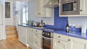 Une cuisine moderne avec des meubles blancs, un plan de travail bleu, un four à micro-ondes encastré et un grille-pain.
