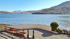 A lakeside view with a bench, a small garden, and a distant mountain range. - 3 bedroom accommodation in Portree (Portree)