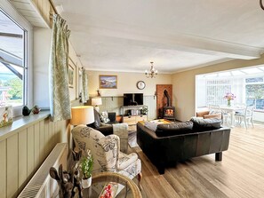 A cozy living room with a fireplace, comfortable seating, a television, and a view through large windows. - 2 bedroom accommodation in Ellesmere (Ellesmere)