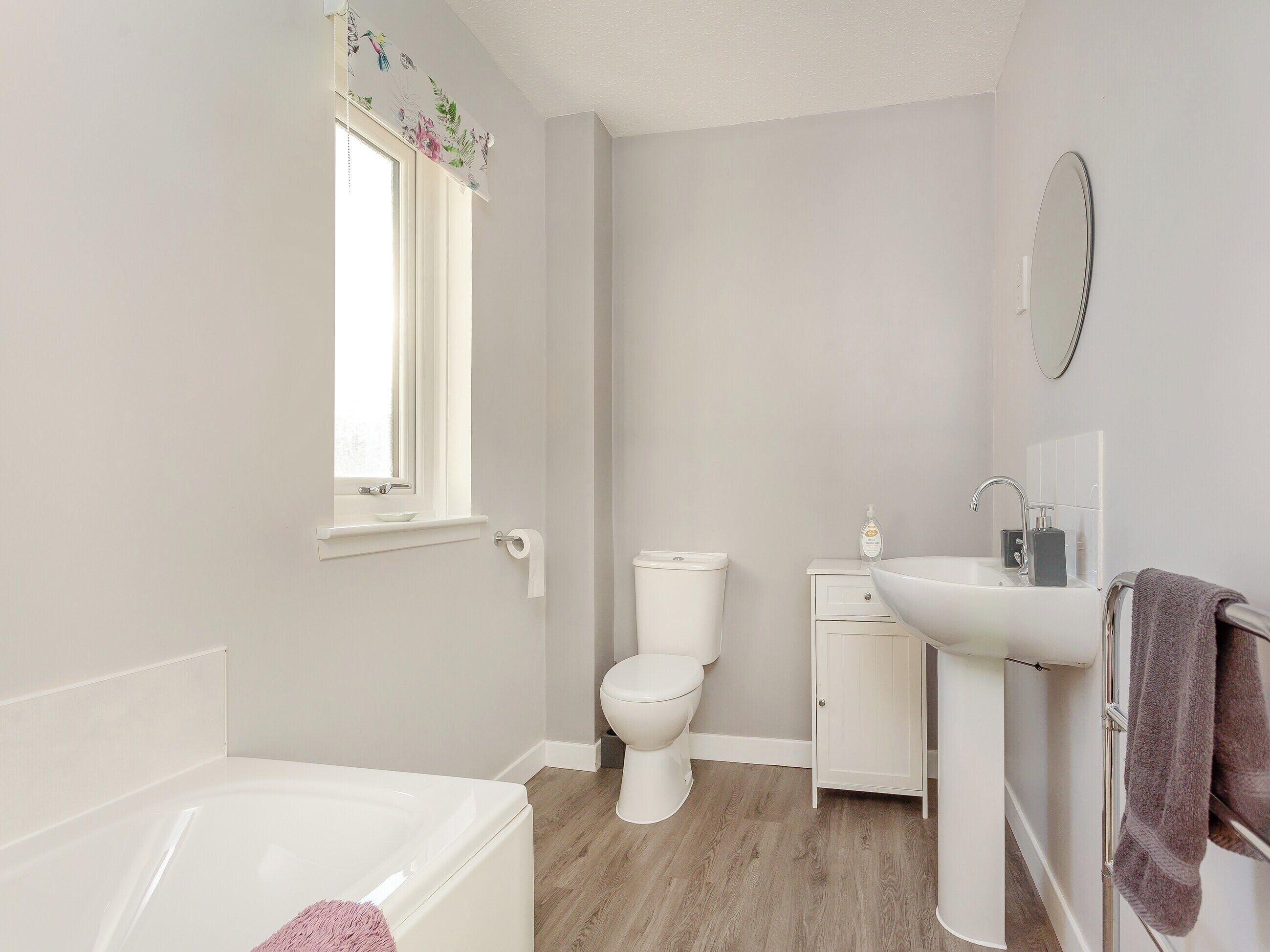 A modern bathroom with a bathtub, toilet, sink, and mirror.