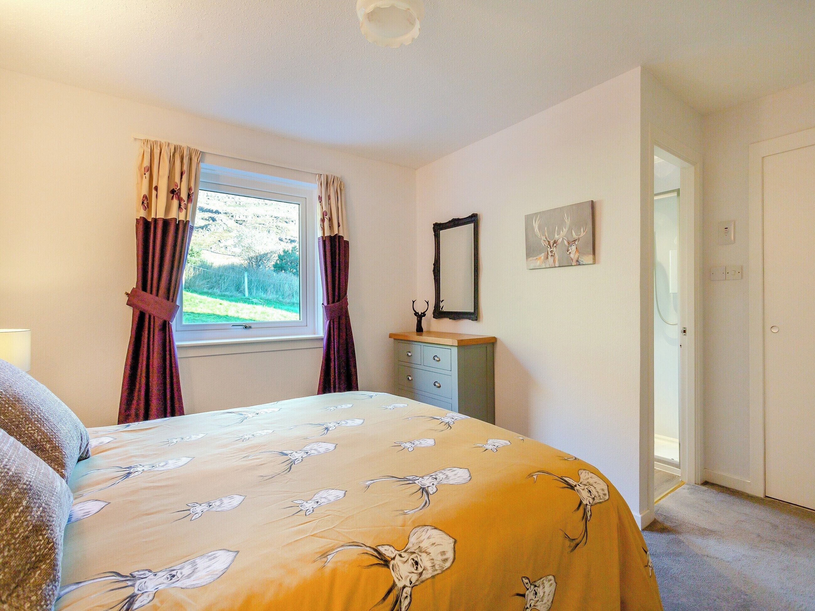 A bedroom with a bed, a dresser, a window with curtains, a mirror, and a picture on the wall.