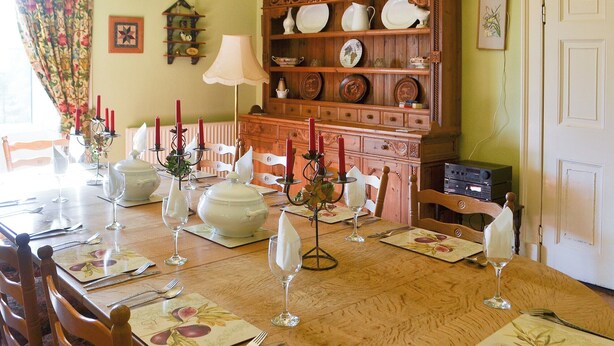 A dining room with a wooden table set for a meal, surrounded by chairs. - 5 bedroom accommodation in Byrness Village, near Otterburn (Byrness Village, near Otterburn)