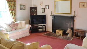 A living room with a sofa, television, fireplace, and decorative items. - 5 bedroom accommodation in Byrness Village, near Otterburn (Byrness Village, near Otterburn)
