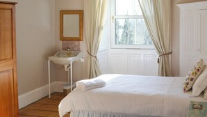 A bedroom with two beds, a bedside table, a mirror, and a window with curtains. - 5 bedroom accommodation in Byrness Village, near Otterburn (Byrness Village, near Otterburn)