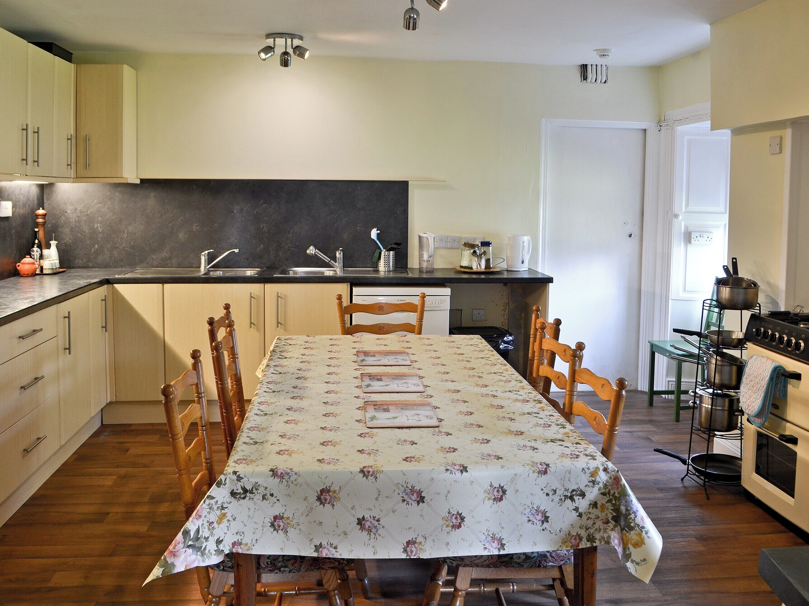 A kitchen with wooden cabinets, a dining table with chairs, a stove, and a sink.