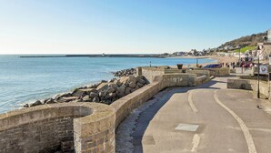A coastal promenade with a stone wall, a paved walkway, and a view of the sea and beach. - 0 bedroom accommodation in Seatown (Seatown)