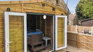 A wooden cabin with a hot tub, a small table, and a bench. - 3 bedroom accommodation in Cutthorpe, near Chesterfield (Cutthorpe, near Chesterfield)