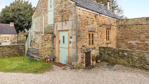 A stone house with a gabled roof, a small balcony, and a gravel driveway. - 3 bedroom accommodation in Cutthorpe, near Chesterfield (Cutthorpe, near Chesterfield)
