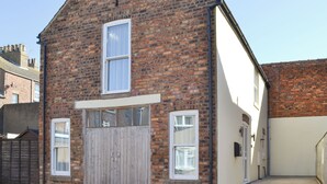 Un bâtiment en briques doté d’une grande porte de garage, d’une petite fenêtre et d’une porte surmontée d’une fenêtre.
