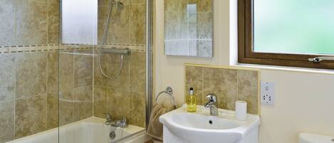 Un baño con cabina de ducha de vidrio, un lavabo con espejo y una ventana.