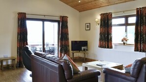 A living room with a leather sofa, a small wooden table, and a TV on a stand. - 3 bedroom accommodation in Burgh le Marsh, near Skegness (Burgh le Marsh, near Skegness)