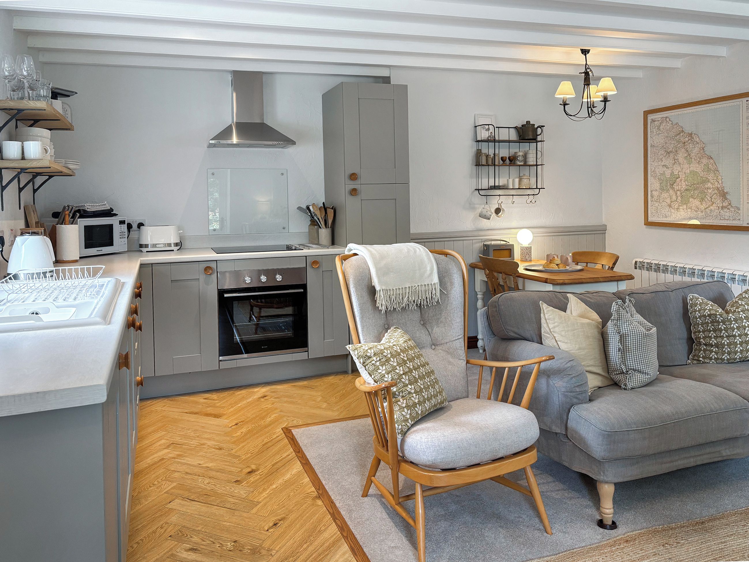 A modern kitchen with a built-in oven, a dining area with a table and chairs, and a cozy seating area with a sofa and a chair.