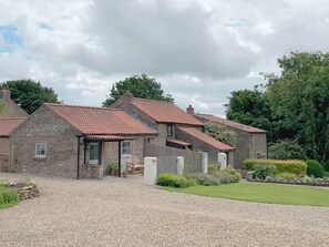 Ein Steinhaus mit Kiesweg und Rasenfläche.
