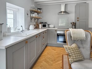 Una cucina moderna con una grande isola, mobili bianchi e un pavimento in legno a spina di pesce.