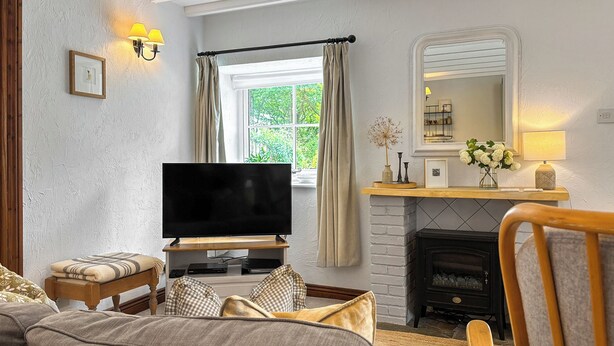 Quarto aconchegante com televisão, lareira e janela com cortinas.