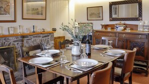 Une salle à manger avec une cheminée en pierre, des meubles en bois et des œuvres d’art encadrées accrochées aux murs.