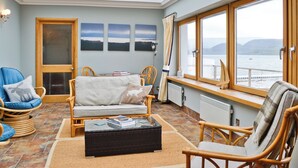 A cozy living room with a sofa, chairs, a coffee table, and a large window with a view of the sea. - 4 bedroom accommodation in Tighnabruaich (Tighnabruaich)