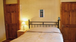 Ein Schlafzimmer mit einem Bett, einem Holzschrank und einem Nachttisch mit Lampe.