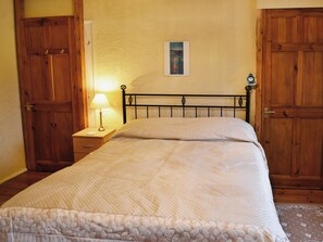 A bedroom with a bed, wooden wardrobe, and a nightstand with a lamp. - 3 bedroom accommodation in Brixham (Brixham)