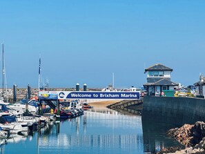 A marina with boats docked, a sign welcoming visitors to Brixham Marina, and a control tower. - 3 bedroom accommodation in Brixham (Brixham)