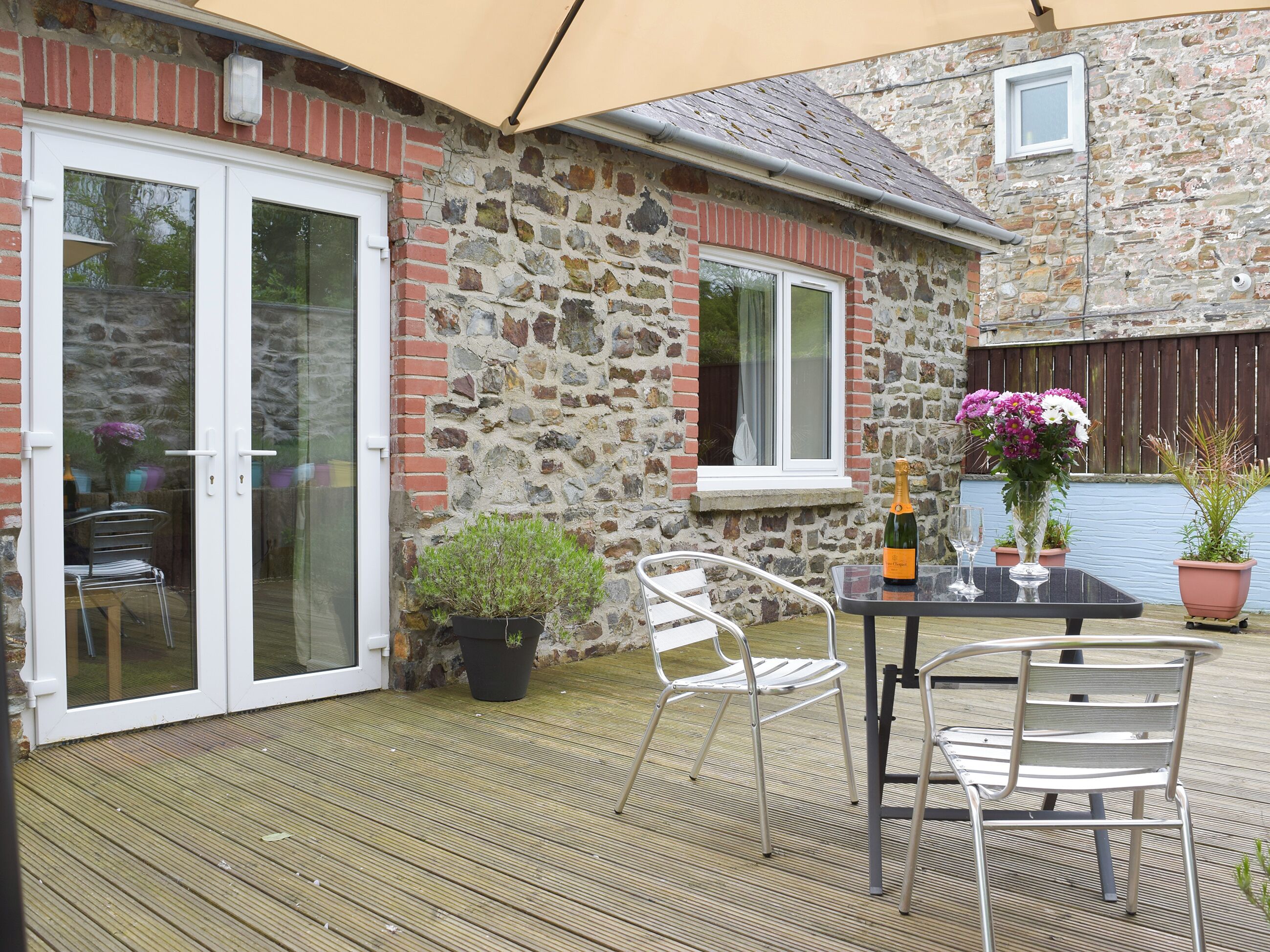 En terrasse med et bord, stole, en champagneflaske og krukkeplanter.