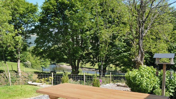 A picnic table in a park with a lake and trees in the background. - 2 bedroom accommodation in Portinscale, near Keswick (near Portinscale)