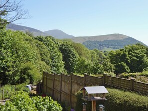 A wooden fence, a birdhouse, and a view of hills.