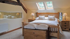 Un dormitorio con una cama de madera, dos mesitas de noche con lámparas, una ventana y un radiador.