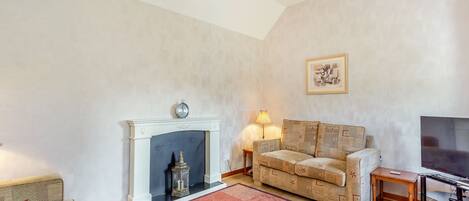 A living room with a fireplace, sofa, TV, and a rug.