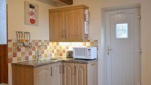 A kitchen with wooden cabinets, a microwave, and a sink. - 2 bedroom accommodation in Carthamartha, near Launceston (Carthamartha, near Launceston)