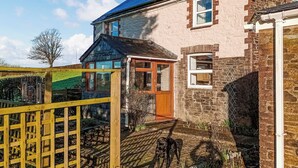 A two-story stone house with a blue roof, a wooden door, and a fenced garden area. - 2 bedroom accommodation in Carthamartha, near Launceston (Carthamartha, near Launceston)
