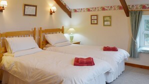 A double bed with white linens and two red towels, a nightstand with a lamp, and floral wall decor. - 2 bedroom accommodation in Carthamartha, near Launceston (Carthamartha, near Launceston)