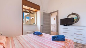 Une chambre à coucher avec un lit, une télévision, une commode et une fenêtre.