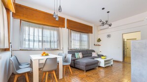 Un salon moderne avec un coin repas, comprenant un canapé, des fauteuils, une table et un comptoir de cuisine.