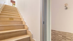 Un escalier en bois avec une rampe et un mur orné d’un motif texturé.