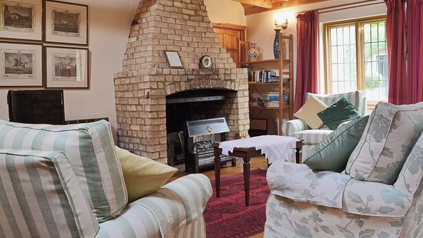Ein gemütliches Wohnzimmer mit Kamin aus Backstein, gestreifter Couch und Bücherregal.