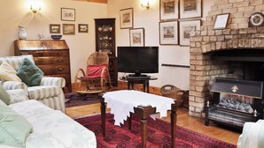 Ein gemütliches Wohnzimmer mit Kamin, Holzmöbeln und gerahmten Bildern an den Wänden.