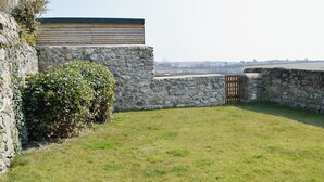 A stone wall, a wooden structure, and a grassy area. - 2 bedroom accommodation in Near Abersoch (Near Abersoch)