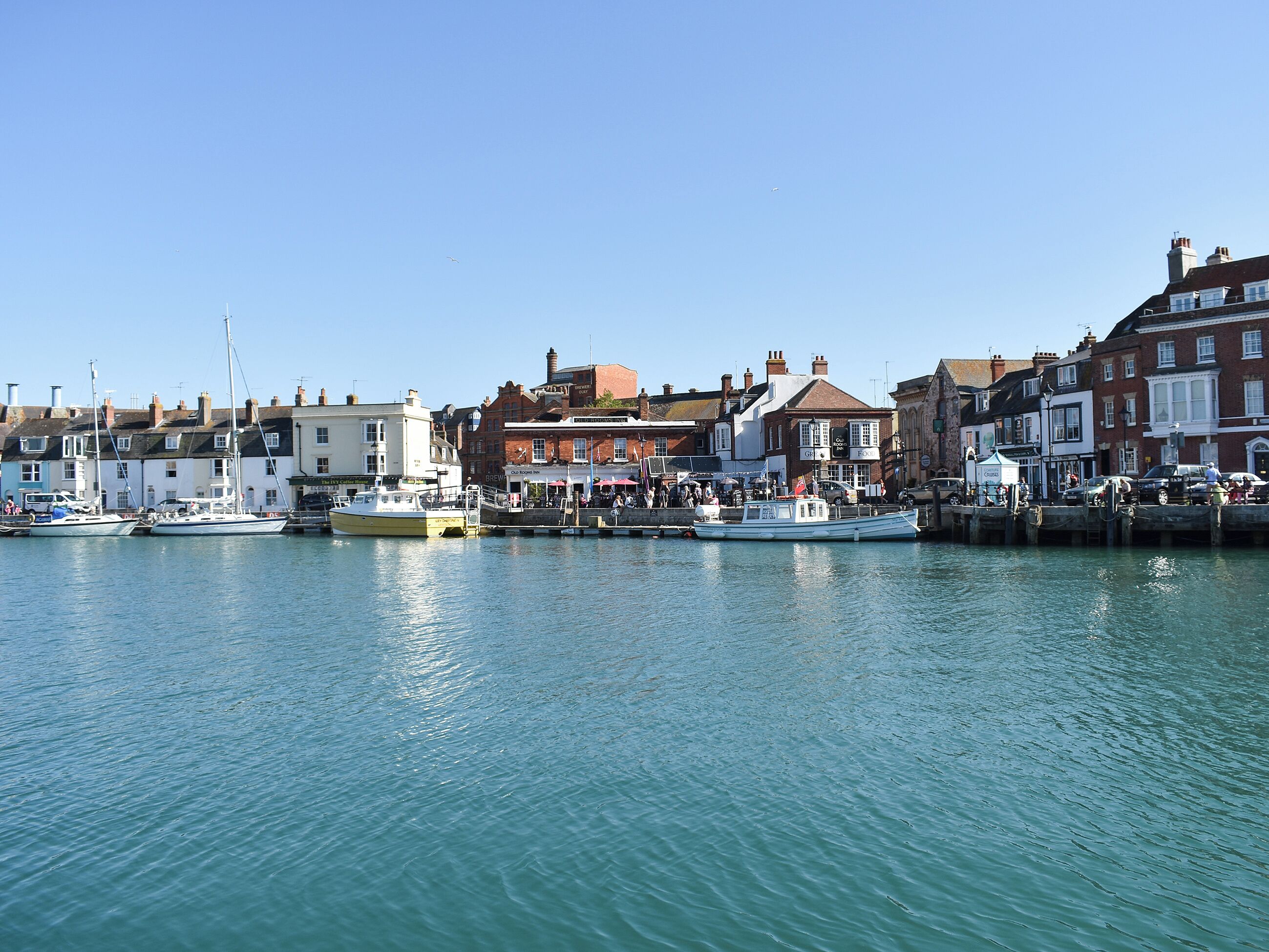 A harbor with boats docked, buildings with shops, and a clear sky.