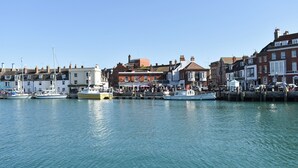 A harbor with boats docked, buildings with shops, and a clear sky.