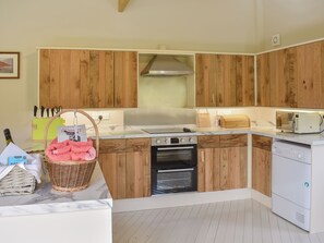 A kitchen with wooden cabinets, a stove, oven, microwave, and a dishwasher.