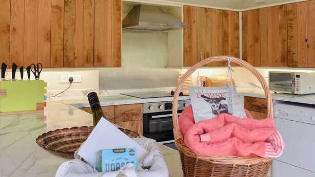 A kitchen with wooden cabinets, a microwave, a toaster, and a wicker basket with a towel and a magazine.