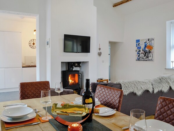 Un comedor con chimenea, un televisor montado encima y un cuadro en la pared.
