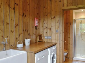 Un interior de madera con lavadora, lavabo e inodoro.