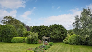 A well-maintained garden with a gazebo, neatly trimmed hedges, and a variety of flowering plants. - 2 bedroom accommodation in Eardisland, near Leominster (Eardisland, near Leominster)