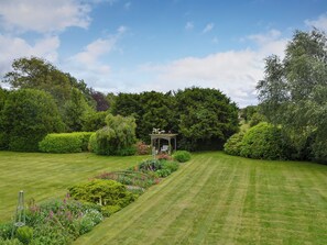 Un jardin bien entretenu, agrémenté d’un belvédère, de haies taillées avec soin et d’une variété de plantes à fleurs.