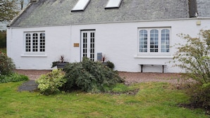 Ein weißes, zweistöckiges Haus mit einem geneigten Dach, Giebeln und einem Schornstein.