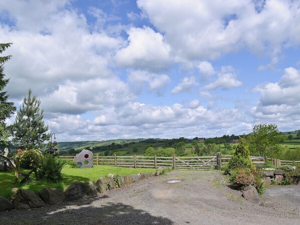 A rural landscape with a gravel path, a wooden fence, and a small building in the distance. - Y Dderwen at Brynglas Farm (Llanfair Caereinion)