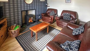 Un salon chaleureux avec une cheminée, des canapés en cuir, une table basse en bois et des tapis à motifs.