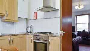 A kitchen with wooden cabinets, a gas stove, an oven, and a kettle.